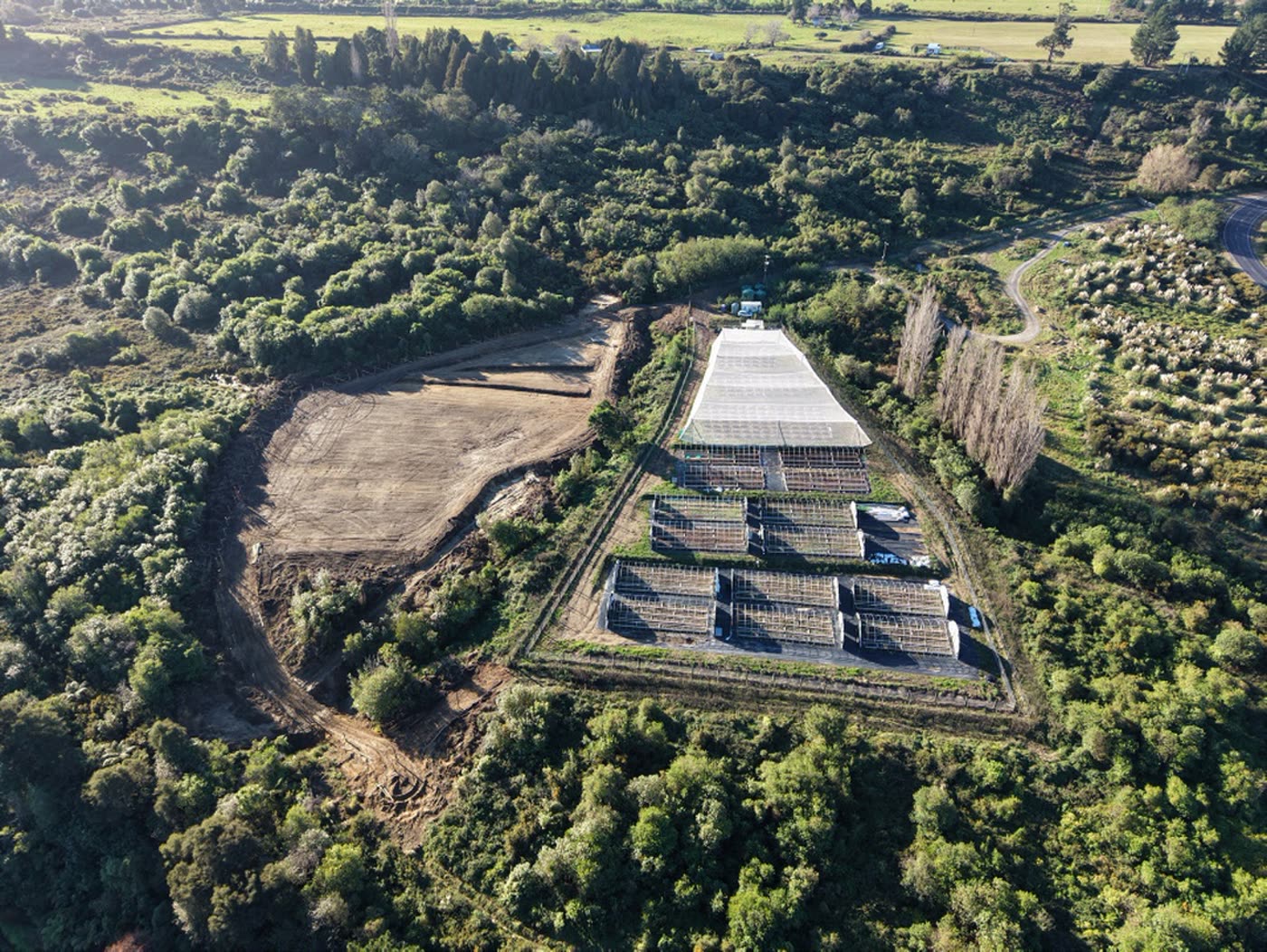 The Aho Farms site from the air — greenhouses, the cleared expansion and the bush-covered hills